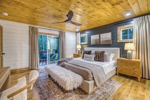 Ein Schlafzimmer mit einem großen Bett, Holzboden und Blick ins Freie.