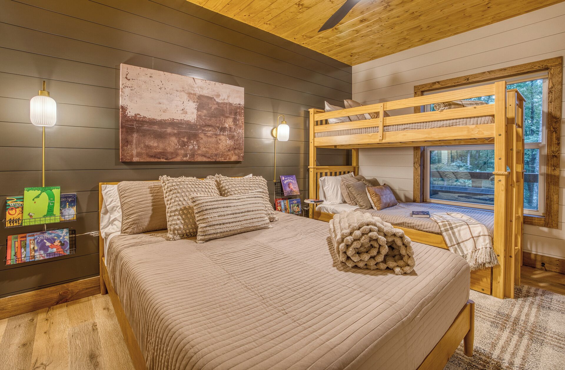 Ein gemütliches Schlafzimmer mit Etagenbett, einem großen Gemälde, Nachttischlampen und einem Bücherregal voller Bücher.