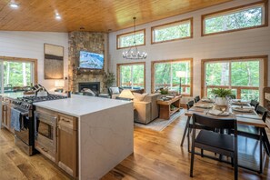 Eine geräumige Küche mit einer großen Kochinsel, ein Essbereich mit einem Holztisch und ein Wohnzimmer mit Kamin.