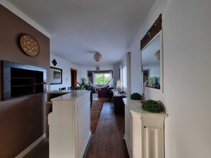 Eine moderne Küche mit Kochinsel, einem Essbereich mit Sofa und einem großen Fenster, das für natürliches Licht sorgt.