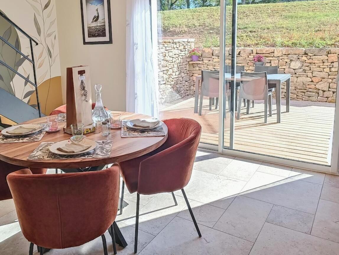 A dining area with a round table, red chairs, and a view of the outdoor patio.