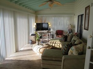 A living room with a sofa, television, and a ceiling fan. - Alligator Tale - Oceanfront in Garden City Beach (Garden City)