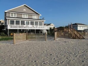 A beachfront house with a balcony, a wooden fence, and a staircase leading to the beach. - Alligator Tale - Oceanfront in Garden City Beach (Garden City)