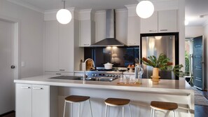 A modern kitchen with a central island, stainless steel appliances, and pendant lighting.