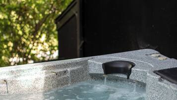 Ein Whirlpool mit Steinverkleidung und Blick auf Grünflächen durch ein Fenster.