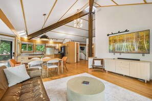 Un interior moderno con zona de comedor, sofá y un cuadro grande en la pared.