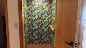 A hallway with a patterned wallpaper, a wooden door, and a wooden floor.