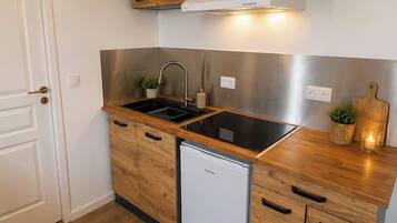 Une cuisine compacte avec des meubles en bois, un lave-vaisselle encastré et un évier en acier inoxydable.