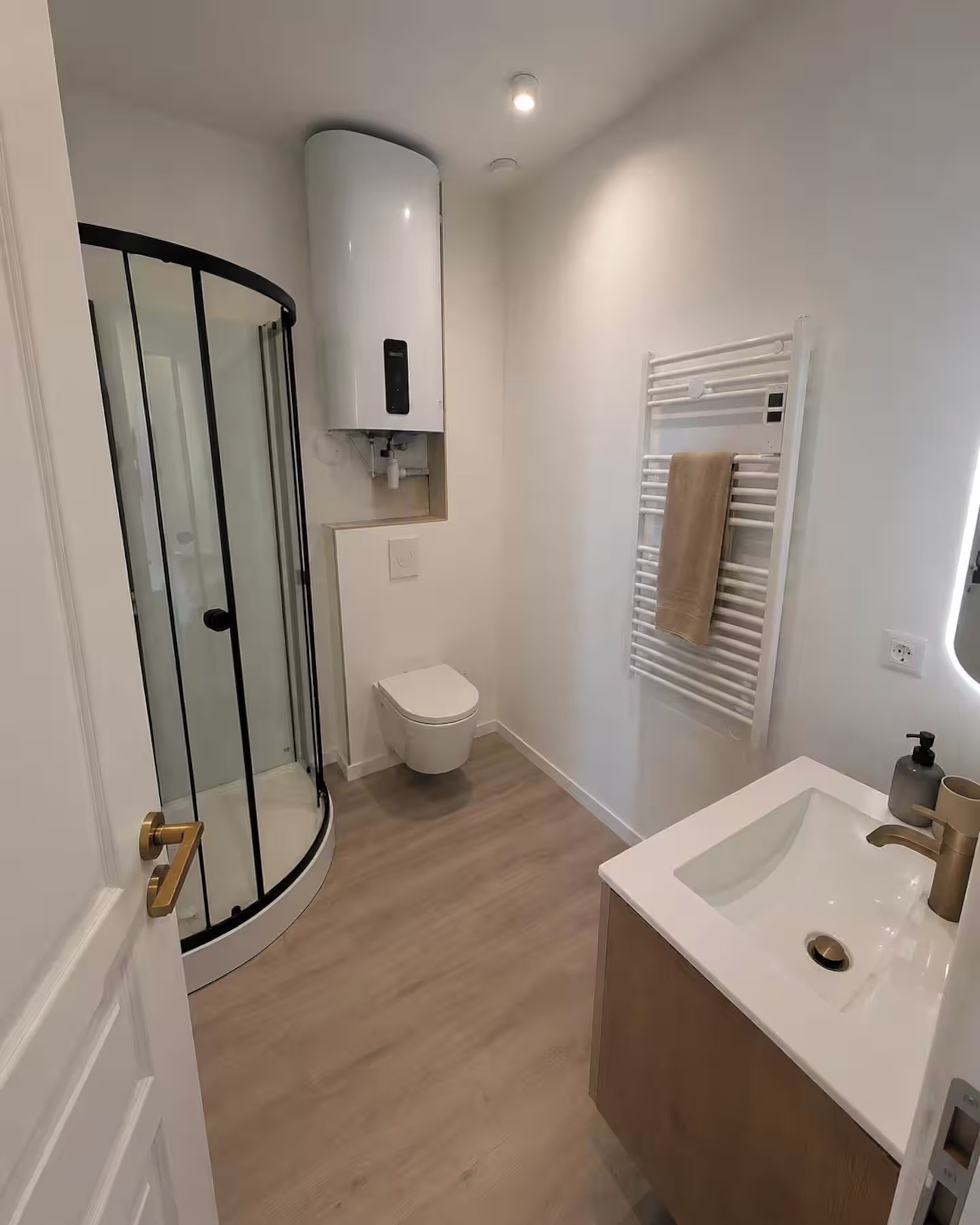 Une salle de bain avec une douche à parois de verre, des toilettes, un lavabo avec un miroir et un porte-serviettes.