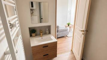 Une salle de bain avec un lavabo blanc, un meuble en bois et un miroir.