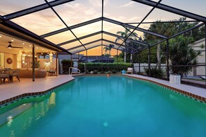 Ein Pool mit Glasdach, umgeben von Liegestühlen und einer Sonnenuhr.