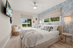 A bedroom with a bed, a ceiling fan, a TV, and a window with a view. - Private Arcade Room, Heated Pool, Fire Pit & Putting Green Near Anna Maria Island (Bradenton)
