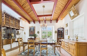 A dining room with a wooden table, chairs, a chandelier, and a large window. - Casa En Cibola in Santa Fe (Santa Fe)