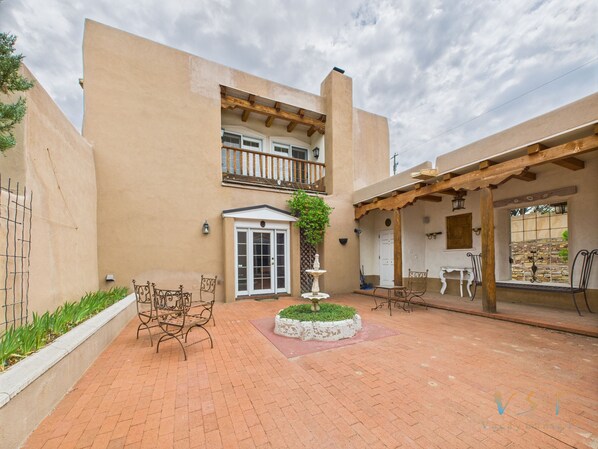 A courtyard with a patio area, a white door, and a small fountain. - Casa En Cibola in Santa Fe (Santa Fe)