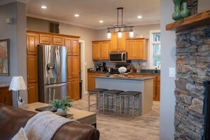 Une cuisine moderne avec des meubles en bois, des appareils électroménagers en acier inoxydable et un îlot central doté de tabourets.
