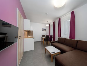 Ein gemütlicher Wohnraum mit Küchenzeile, Essbereich, Sofa und Fernseher.
