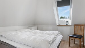 Makuuhuoneessa on sänky, tuoli, ikkuna ja patteri.