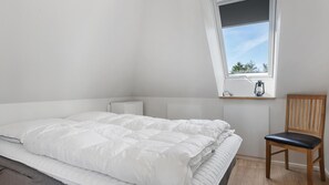 A bedroom with a bed, a chair, a window, and a radiator. - VillaVilla 981 - Hostrup Strand, Limfjorden (Spøttrup)