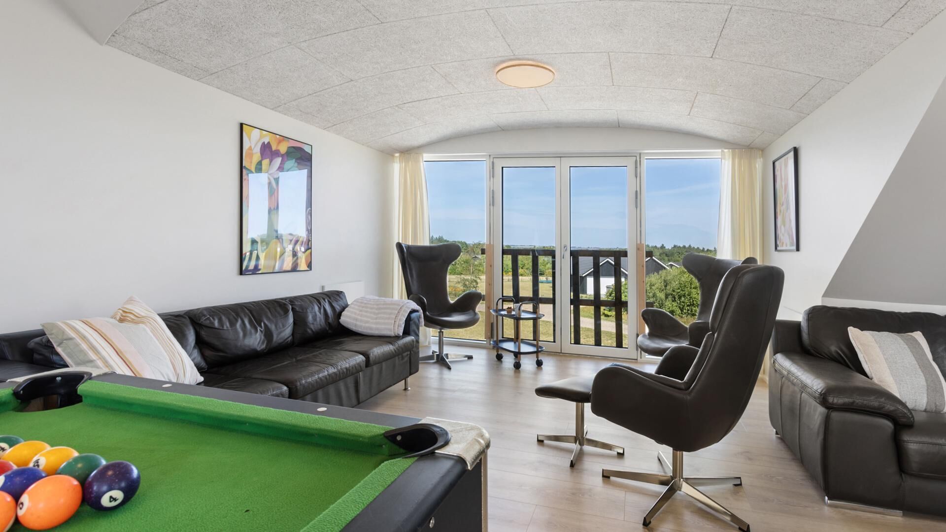 Un salon moderne avec une table de billard, des canapés en cuir et un balcon offrant une vue imprenable.