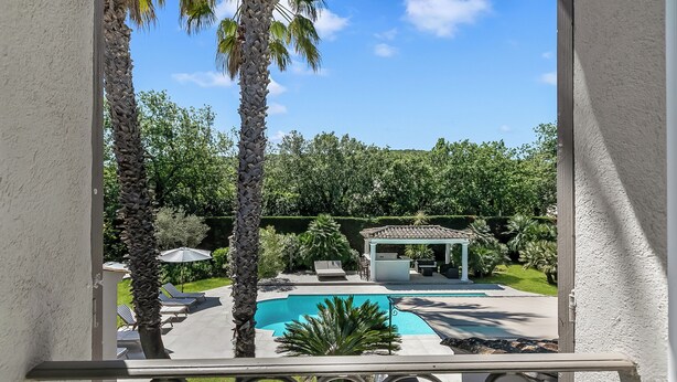 Un espace piscine avec des chaises longues, un kiosque et des palmiers.