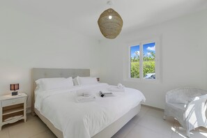 A bedroom with a bed, bedside table, lamp, window, and chair. - Villa Roi Soleil Private pool - St-Tropez, Saint-Tropez, France (Saint-Tropez)