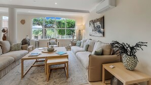 Un salon spacieux avec une grande fenêtre, un canapé, une table basse et une lampe.
