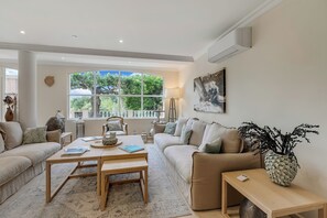 Ein geräumiges Wohnzimmer mit großem Fenster, einer Couch, einem Couchtisch und einer Lampe.