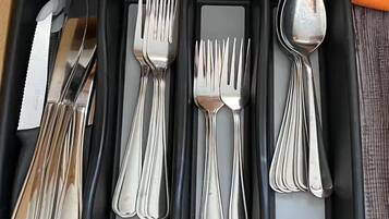 Una bandeja negra con compartimentos que contiene cubiertos, incluyendo tenedores, cuchillos y cucharas.