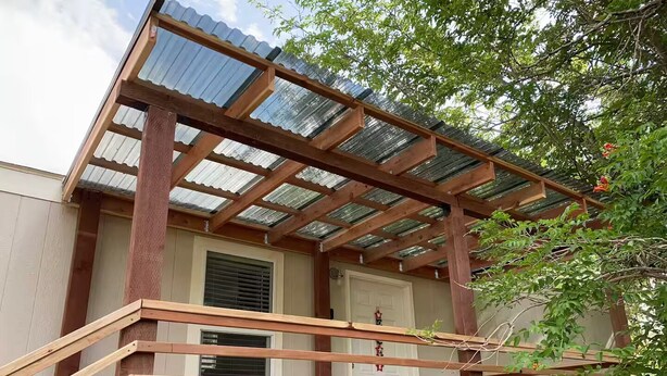 A covered porch with wooden railings and a corrugated metal roof.
