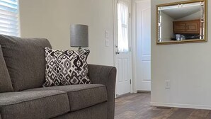 A living room with a grey sofa, patterned throw pillow, and a rug.