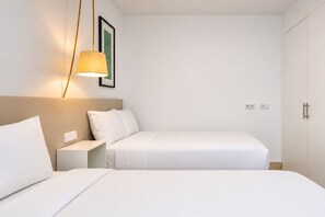 A hotel room with two beds, a bedside table, a wall-mounted light, and a wardrobe. - GuestReady - Villa Salobre Par4 Private Pool (San Bartolomé de Tirajana)