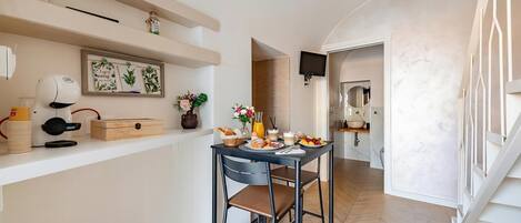 A modern kitchen with a dining area, a coffee machine, and a TV mounted on the wall.