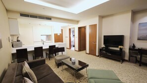 Ein Hotelzimmer mit Wohnbereich, einer Küchenzeile, einem Fernseher und einem Sofa.
