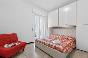 Ein Schlafzimmer mit einem Bett, einem roten Sofa und weißen Schränken.