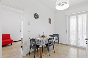 Ein Essbereich mit einem Tisch für vier Personen, einer roten Couch, einer Uhr und einem Fenster mit Vorhängen.