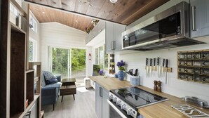 Une cuisine moderne avec un plafond en bois, des appareils électroménagers en acier inoxydable et une vue sur l’extérieur.