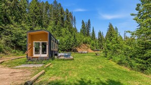 Une cabane dotée d’une grande véranda ouverte, entourée d’une forêt.
