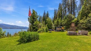 Un chalet offrant une vue sur un lac et des montagnes, entouré d’arbres et doté d’une pelouse bien entretenue.
