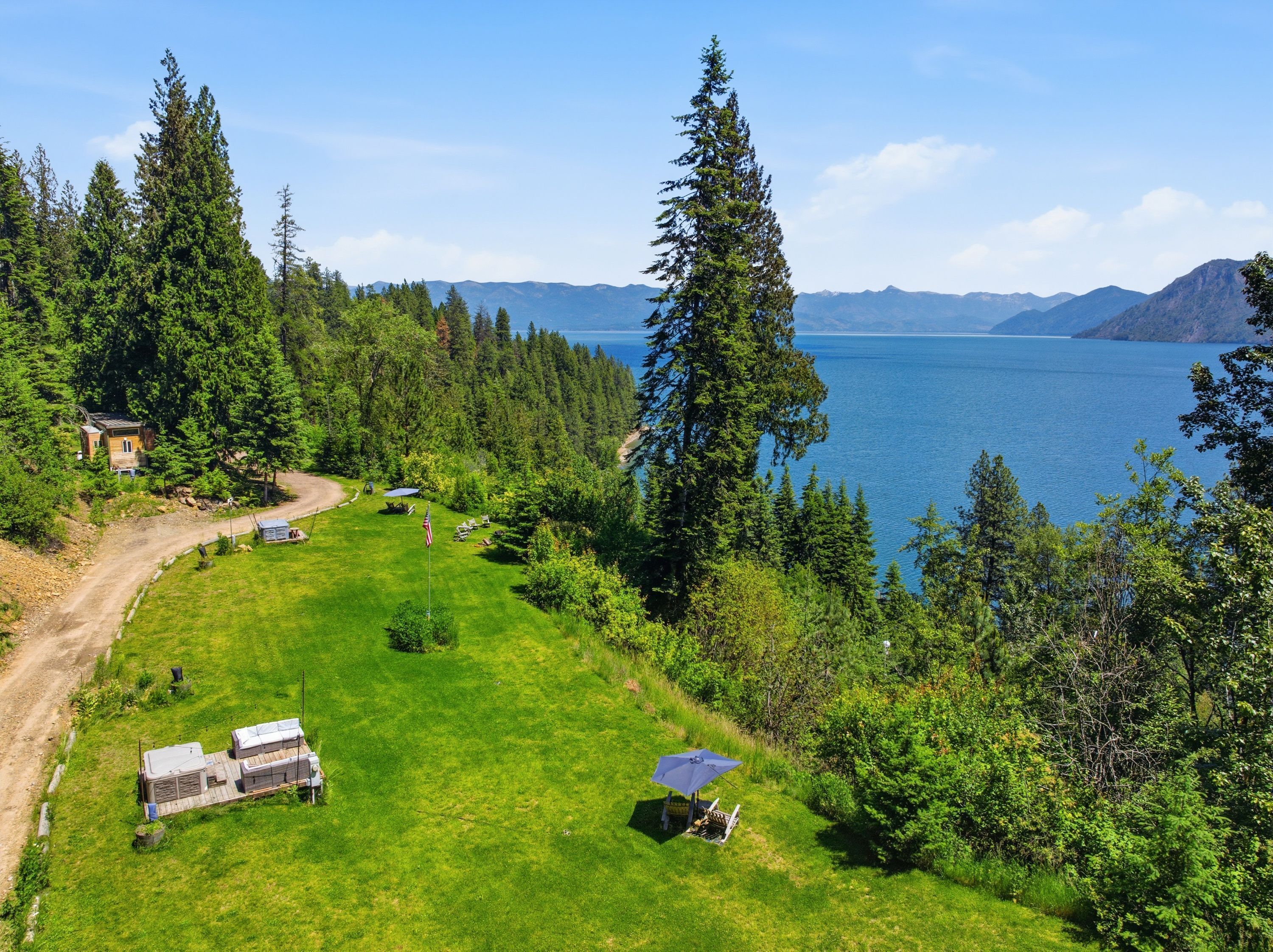 Un chalet isolé, doté d’une terrasse, entouré d’une forêt dense et bordé par un lac.