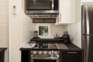 A modern kitchen with a stainless steel stove, microwave, and refrigerator.