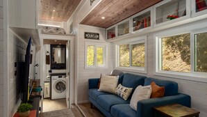 A cozy living area with a blue sofa, a washing machine, and a laundry basket.