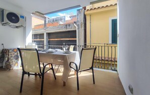 A balcony with a table set for two, chairs, and a view of buildings. - Gorgeous apartment in Mazzeo with WiFi (Mazzeo)
