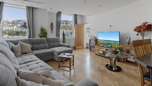 Uma sala de estar moderna com um sofá seccional, uma TV de tela plana e um espaço de refeições com uma mesa de vidro.