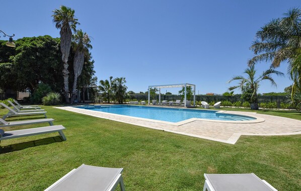 A swimming pool with lounge chairs, a covered seating area, and palm trees. - Nice home in Partinico (Partinico)
