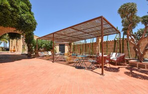 An outdoor patio with a shaded pergola, seating, and cacti. - Nice home in Partinico (Partinico)
