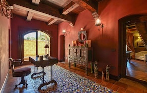 A room with a tiled floor, a desk with a chair, a mirror, and a staircase leading to another room.
