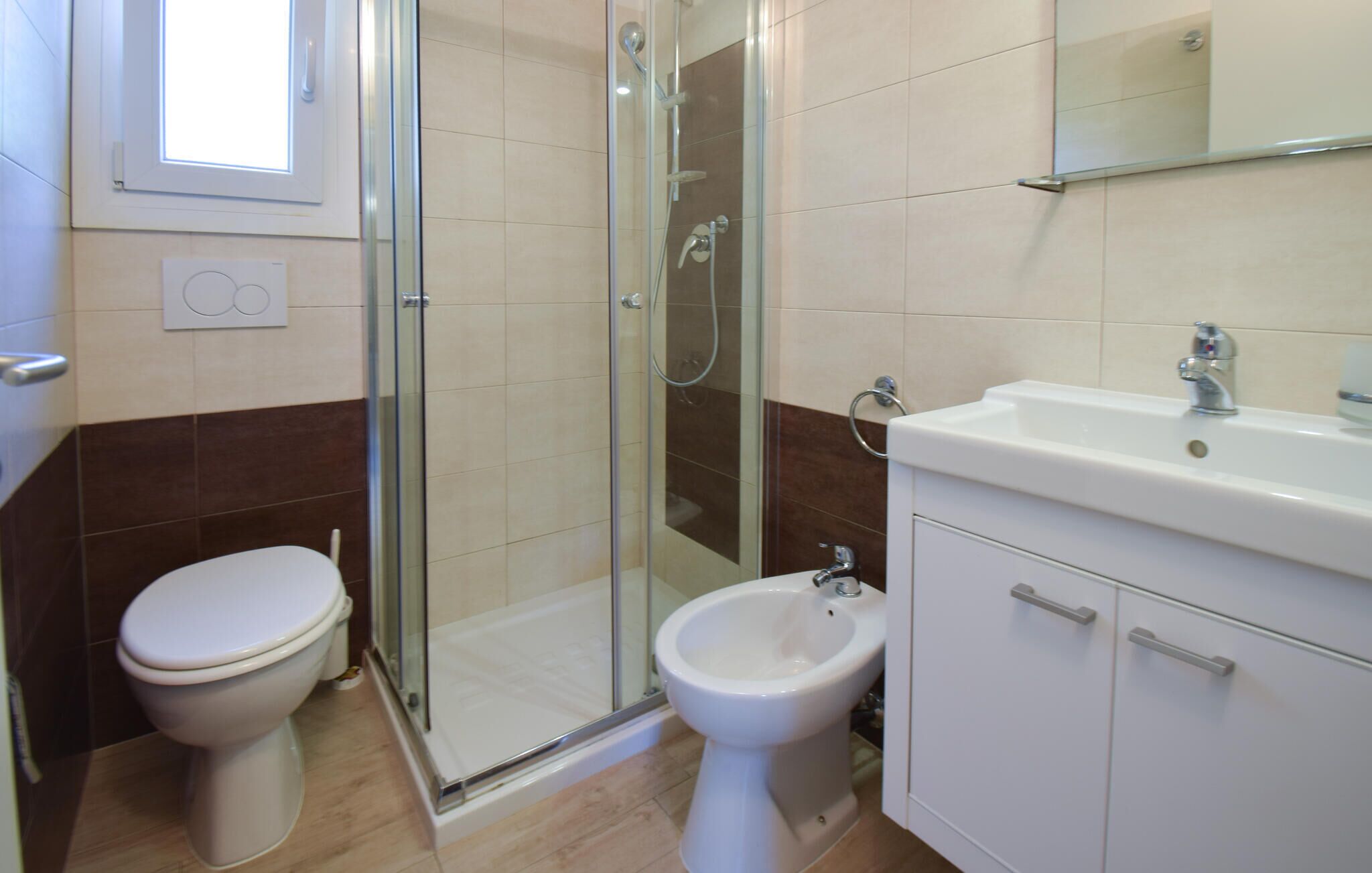 Ein Badezimmer mit Toilette, Bidet, Dusche und Waschbecken.