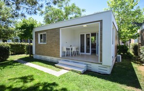 Una casa moderna de un piso con un patio, una mesita y sillas.