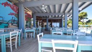 An outdoor dining area with turquoise tables and white chairs, a mural of a beach scene, and a view of the sea. - 2 bedroom beautiful home in Torino di Sangro (Torino di Sangro)