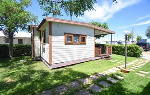 Eine kleine, eingeschossige Holzhütte mit Veranda, einer kleinen Terrasse und einem Fenster.